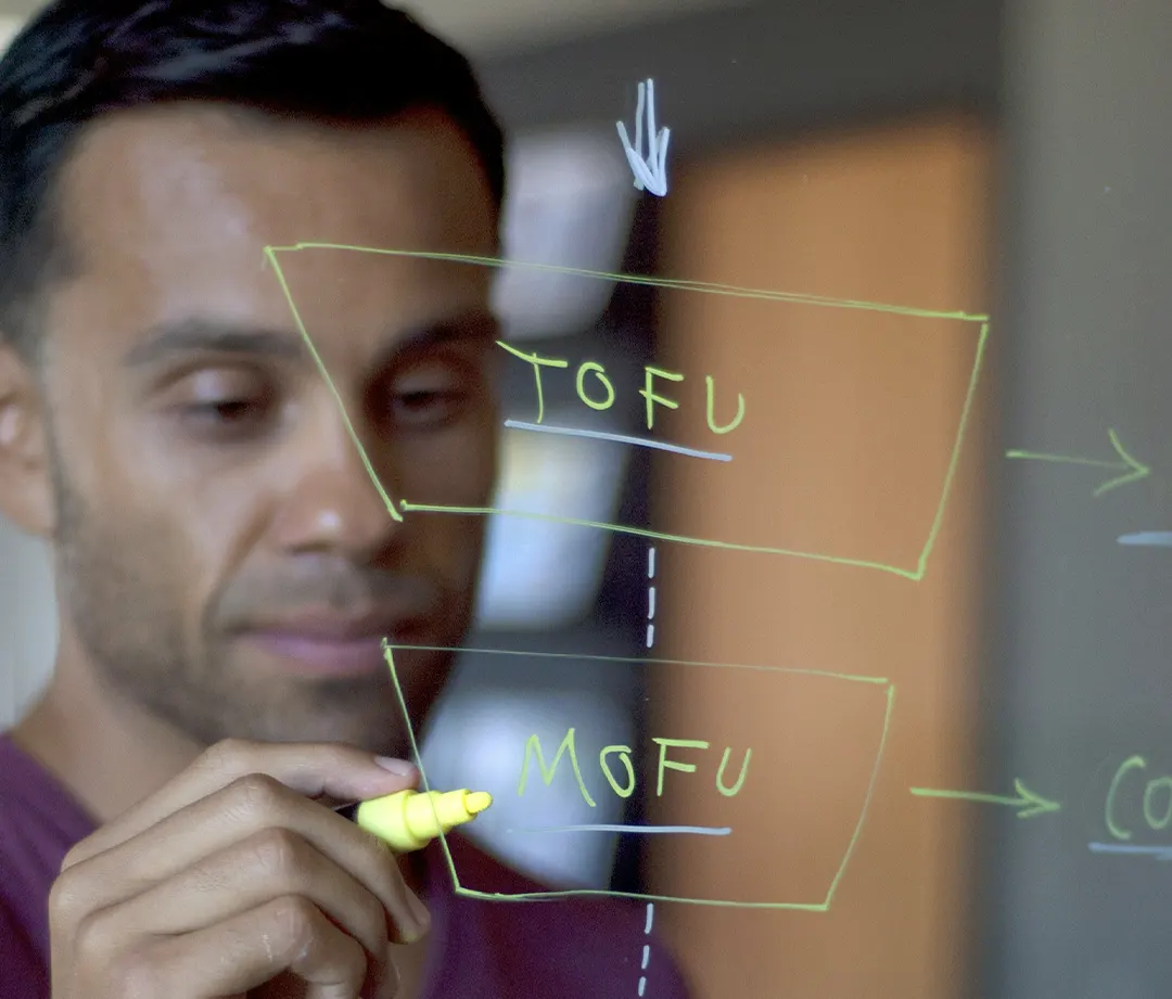 Man writing a marketing funnel on glass, TOFU, MOFU inside a segmented inverted pyramid