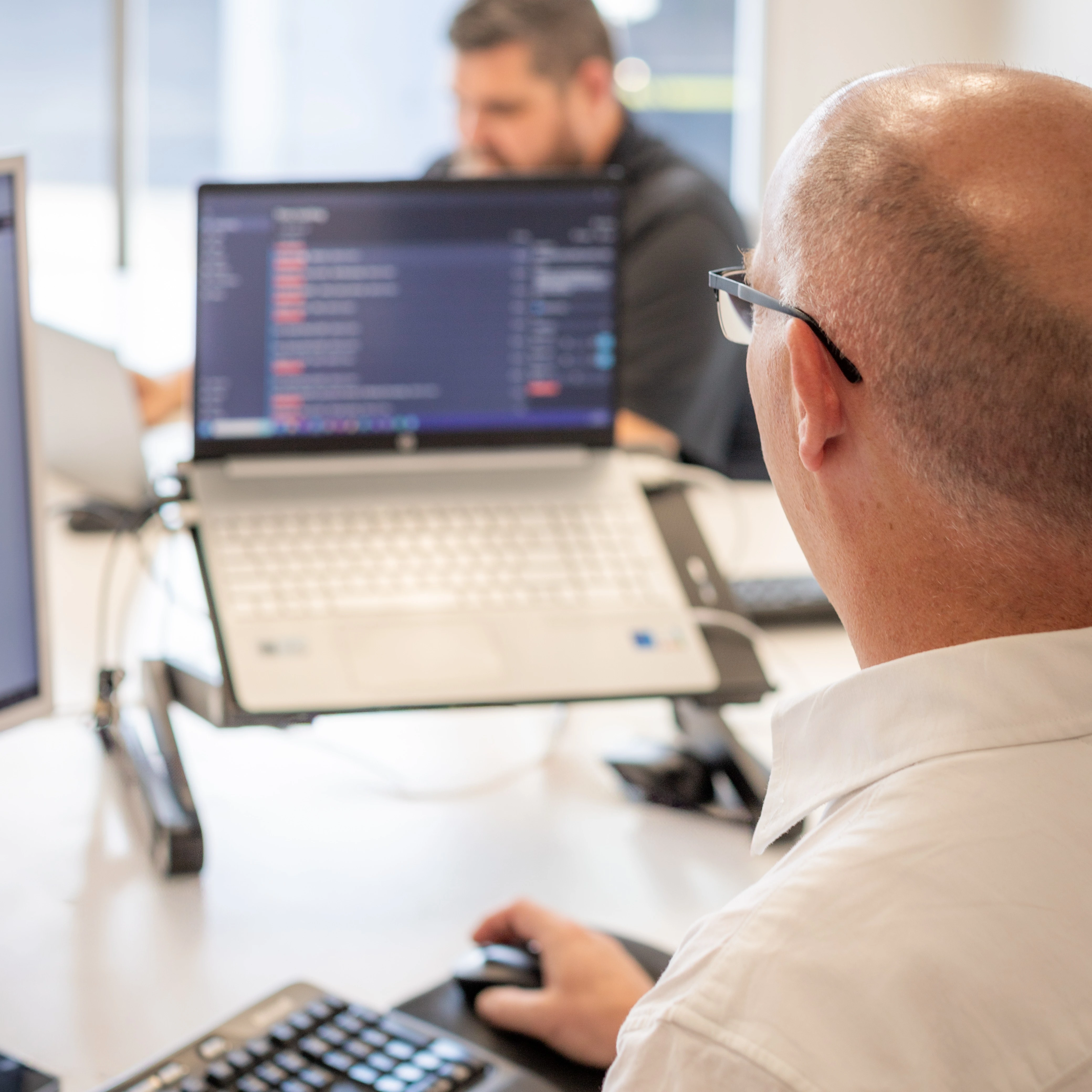 man with a bald head looking and working at a laptop